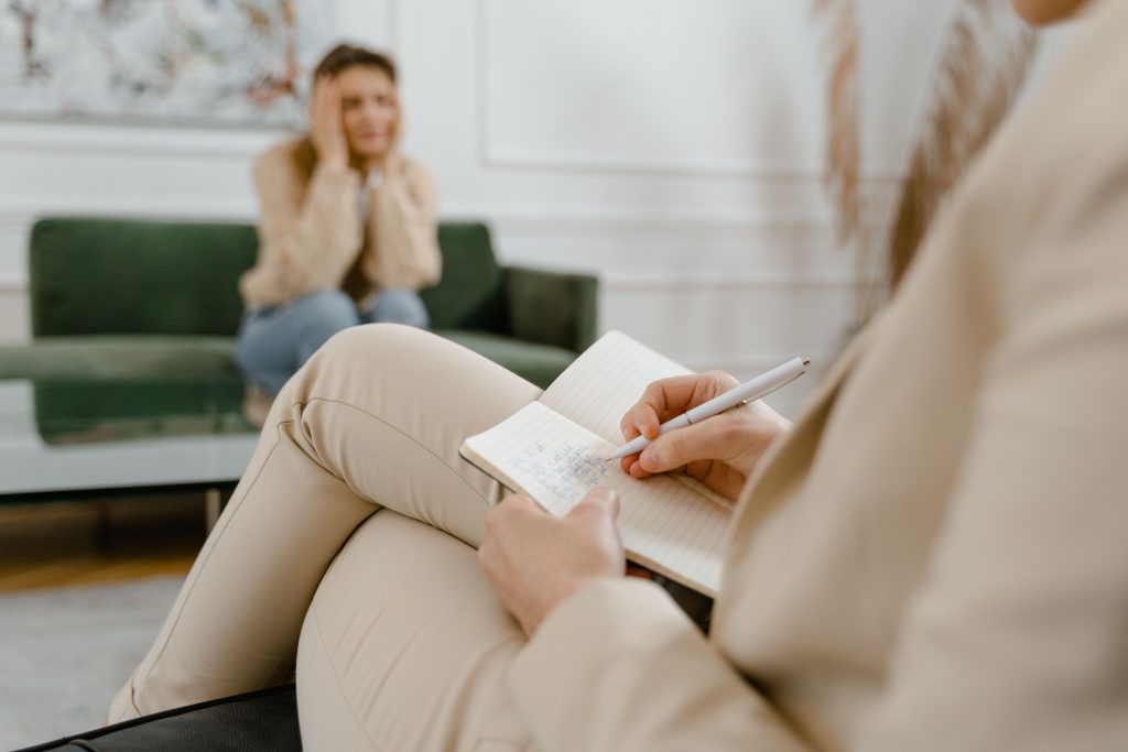 A therapist taking notes during a consultation with a patient, focusing on mental health.